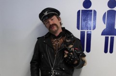 Jamie Oliver with a dog, both dressed up in leather near a sign for mens and ladies toilets. Jamie Oliver with a dog, both dressed up in leather near a sign for mens and ladies toilets.