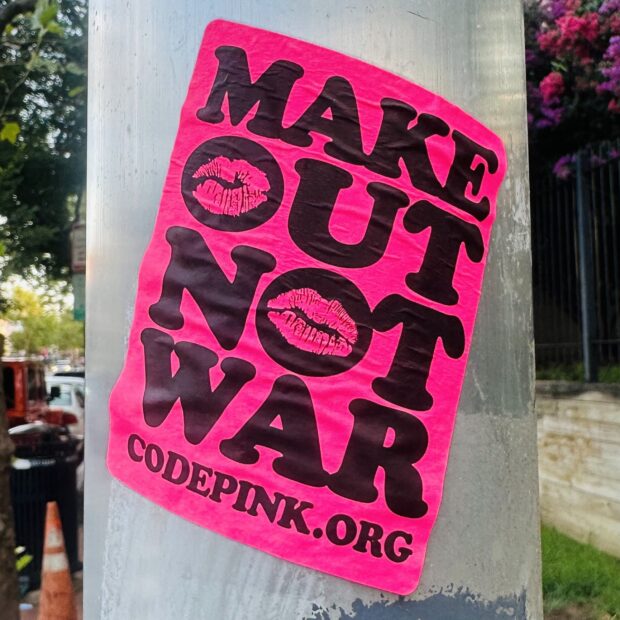 Bright pink sticker from code pink dot org: Make Out Not War.